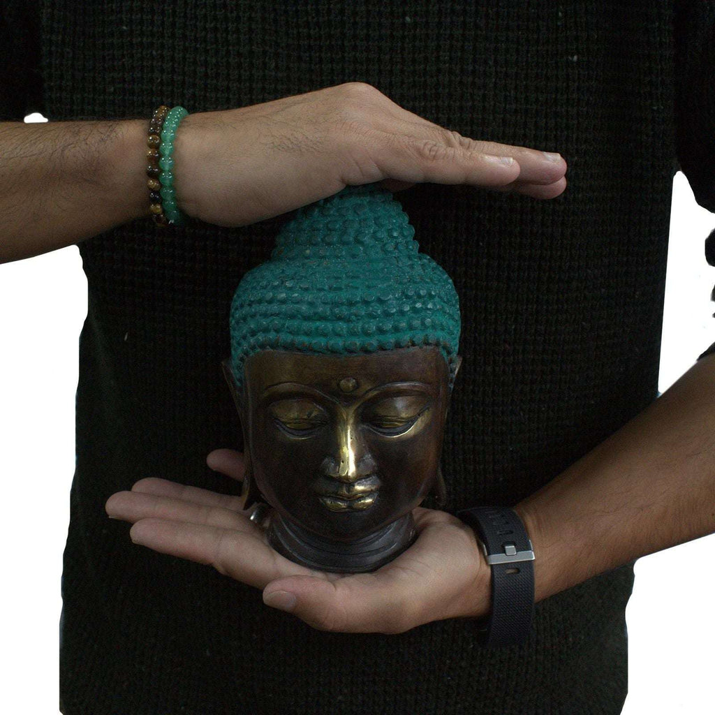 Person holding a Large Classic Brass Buddha Head with a serene expression, featuring detailed craftsmanship and a turquoise patina on the hair.