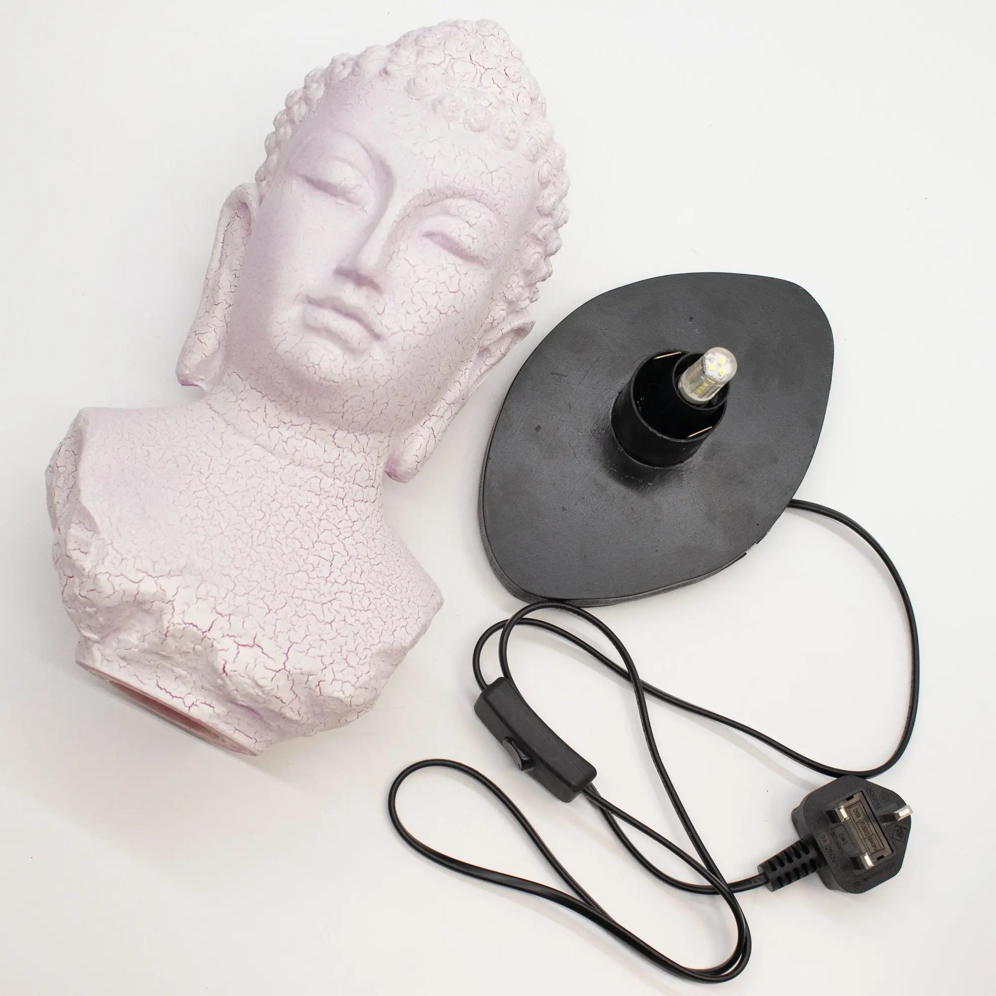 Buddha Bust Lamp Cherry Crackle - Oval stand featuring a pale cherry crackle finish Buddha head bust next to an oval black lamp base with a power cord and switch.