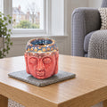 Buddha Oil Burner - Rose & Teal on a stone mat in a British sitting room
