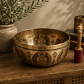 Tibetan Healing Engraved Bowl - 21cm - 5 Buddhas crafted from brass featuring detailed engraved Buddha figures, displayed on a wooden surface with natural light and decorative accents.
