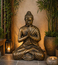 Med Large Antique Gold Praying Buddha Statue - 1.2m Tall seated with hands in prayer position, surrounded by plants and candles in a serene indoor setting.