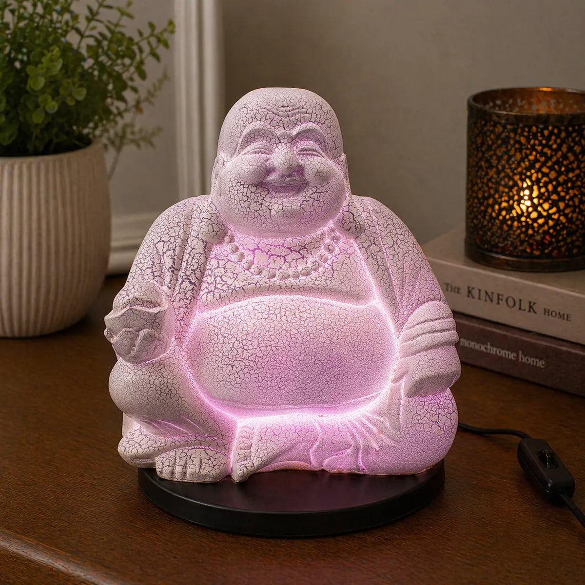 Laughing Buddha Lamp Lavender Crackle - Round Stand showing a glowing lavender crackle finish Buddha statue lamp on a round black base, creating a calming ambiance on a wooden surface.