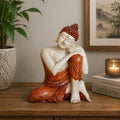 Hand Carved Buddha Statue - 25cm Thinking in warm earthy tones sitting thoughtfully on a wooden surface beside a lit candle and decorative books, creating a peaceful atmosphere.