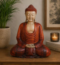 Hand Carved Buddha Statue - 40cm Hand Down sitting peacefully with a serene expression, detailed wooden texture, displayed on a wooden surface with indoor plant and candle decor.