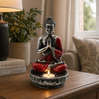 Buddha Candle Holder - Red - Medium featuring a hand-painted Buddha statue in red and black with intricate details, holding a lit tealight candle on a decorative base.