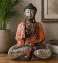 Vintage Orange Hand Carved Buddha Statue - 60cm - Teaching Transmission with a distressed finish, seated in meditation pose, placed on a wooden surface beside books and a plant.