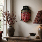 Wall-mounted Home Decoration Buddha Head - 25cm - Red Shine Finish with intricate detailing, displayed above a rustic wooden table holding books, pottery, and a lamp.