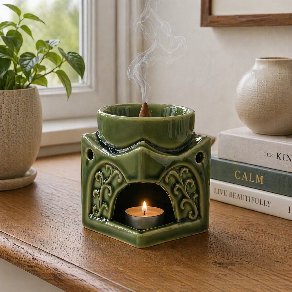 Square Buddha Burner - Dark Jade ceramic oil burner with intricate carved details, lit tealight candle underneath, and incense cone releasing smoke in a cozy indoor setting.