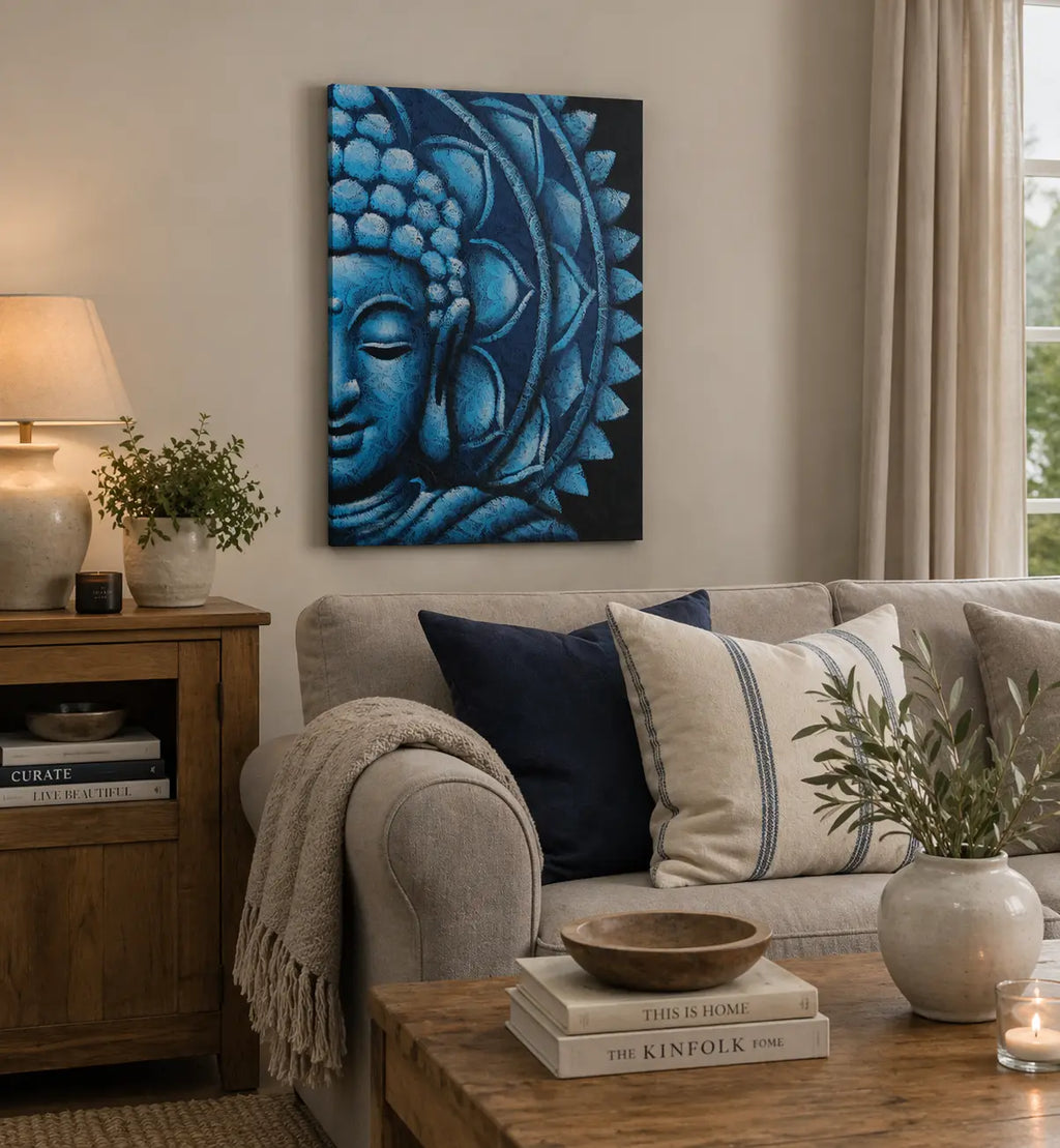 Blue Half Buddha Mandala 60x80cm hanging on a beige wall above a cozy living room sofa with neutral cushions, next to a wooden cabinet, lamp, and green plants.