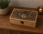 Big Rectangle Box 21.5x14x6.3cm - Buddha Face Black Engraved wooden box with intricate Buddha design, placed on a wooden surface next to a small plant and lit candle.
