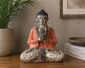 Vintage Orange Hand Carved Buddha Statue - 30cm - Welcome seated in a meditative pose with hands in prayer, featuring a distressed orange and cream finish, displayed on a wooden surface.
