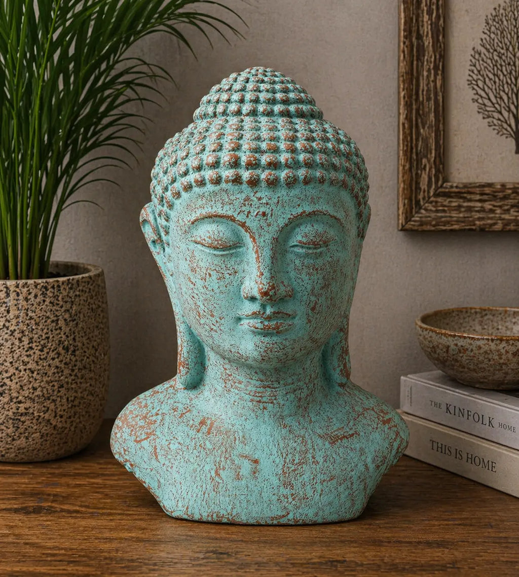 Tranquility Buddha Head - Green Copper statue with a serene expression, featuring a rustic green copper finish, displayed on a wooden surface with modern decor elements.