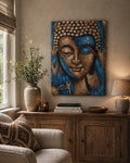 Buddha Painting - Bronze & Blue Flower 75x55cm hanging on a beige wall above a wooden sideboard, with a ceramic vase, books, and a lamp in a cozy living room setting.