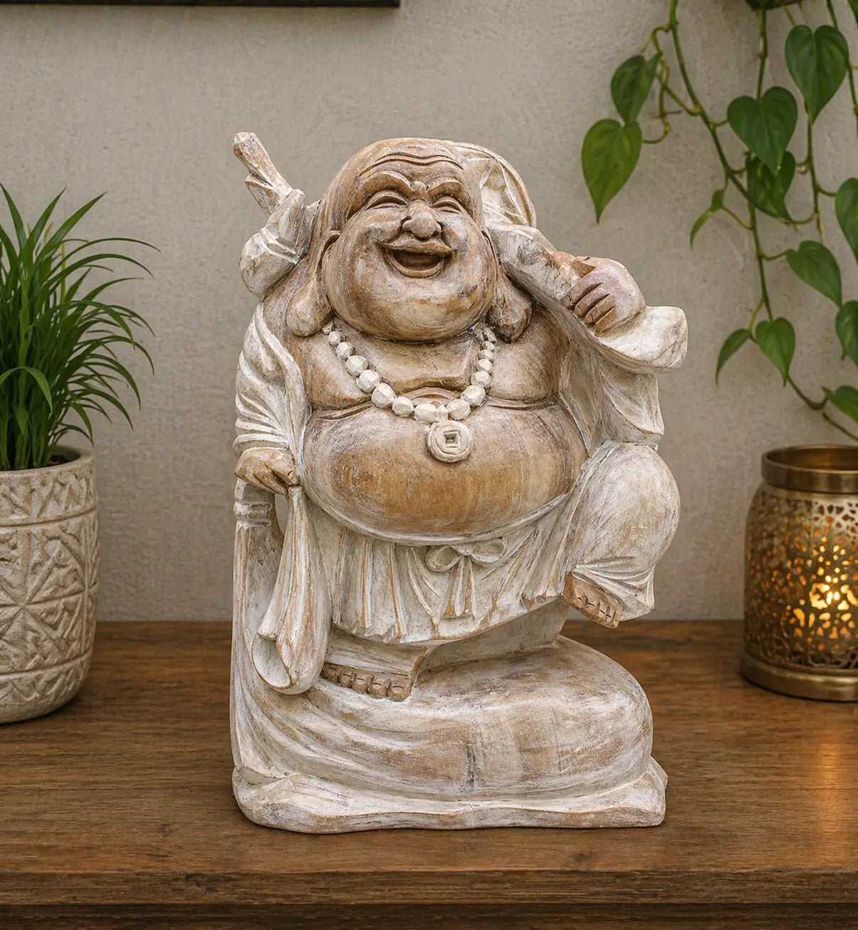 Happy Buddha Bring Wood - Whitewash 30cm, a hand-carved statue with a joyful expression, rustic whitewashed finish, displayed on a wooden surface with plants and ambient lighting.