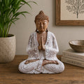 Buddha Statue Whitewash - 30cm Welcome showing a serene seated Buddha with hands in prayer position, featuring a whitewashed finish and detailed robes, placed on a wooden surface with decorative plants and books in the background.