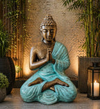 Med Large Turquoise & Gold Praying Buddha Statue - 1.2m Tall seated in meditation with hands in prayer pose, featuring turquoise robe and gold textured finish amidst calming plants and candlelight.