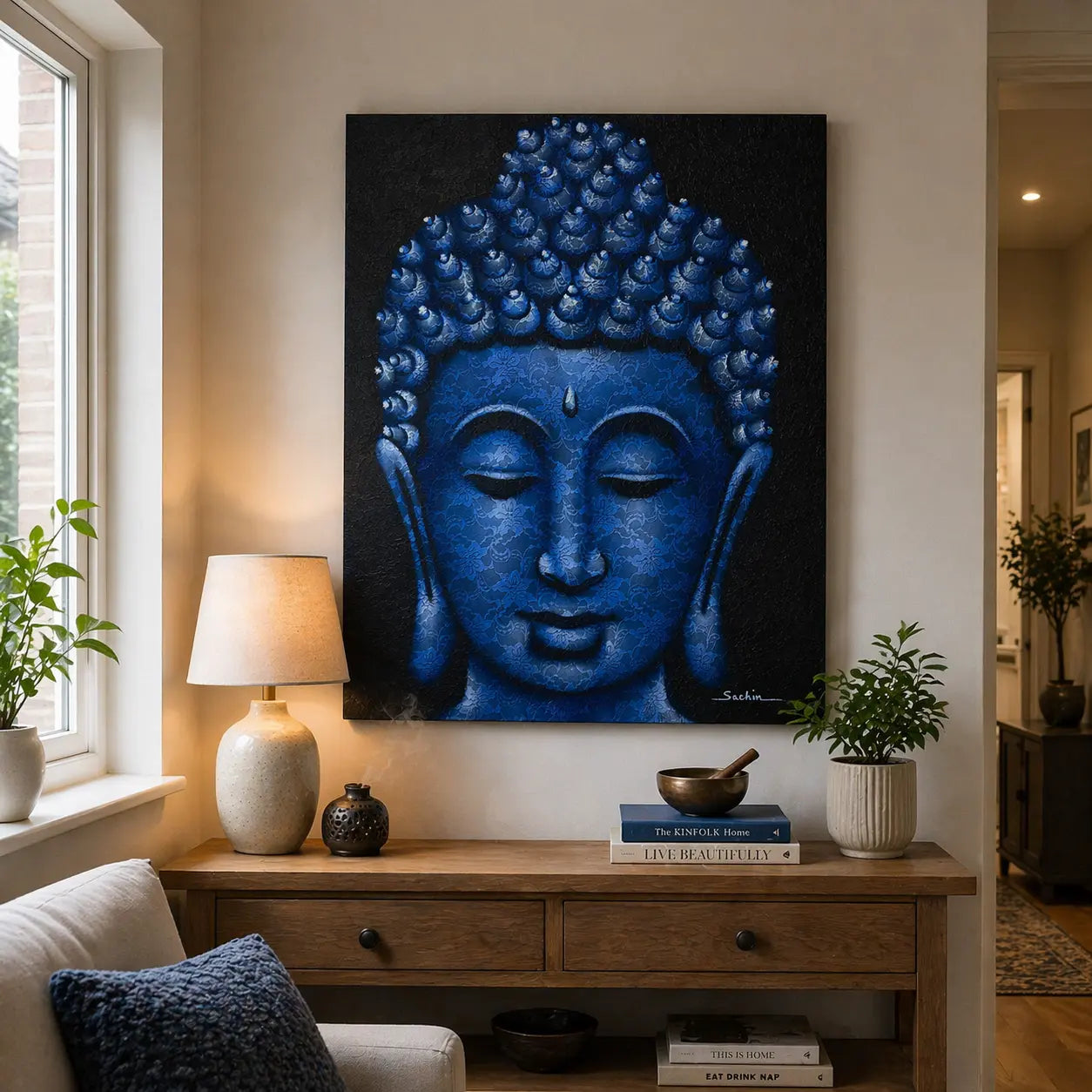Buddah Painting - Blue Brocade Detail featuring a serene blue Buddha face with intricate brocade patterns, displayed above a wooden table with decorative items in a cozy living space.