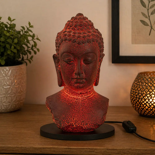 Buddha Bust Lamp Molton Lava - Oval stand casting a warm red glow, featuring a textured lava finish on a black oval base, positioned on a wooden surface near decorative items.
