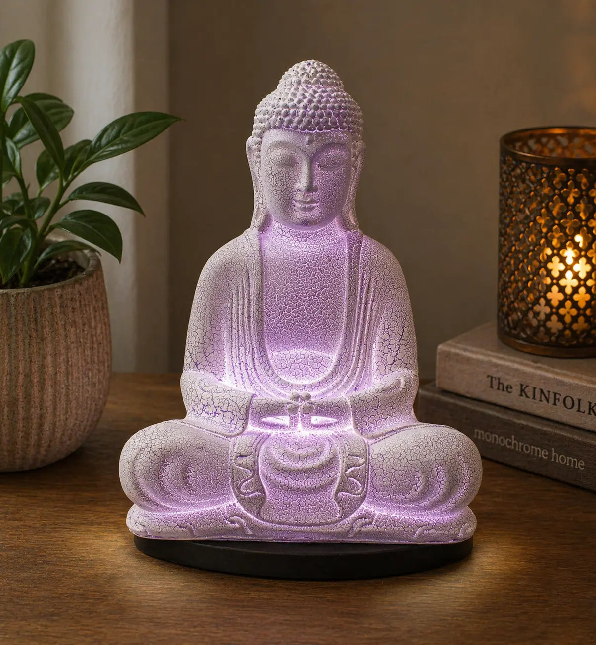 Meditation Buddha Lamp Lavender Crackle - Oval Stand featuring a softly glowing lavender resin Buddha statue with a crackle finish, placed on an oval black base beside a lit candle and plant.
