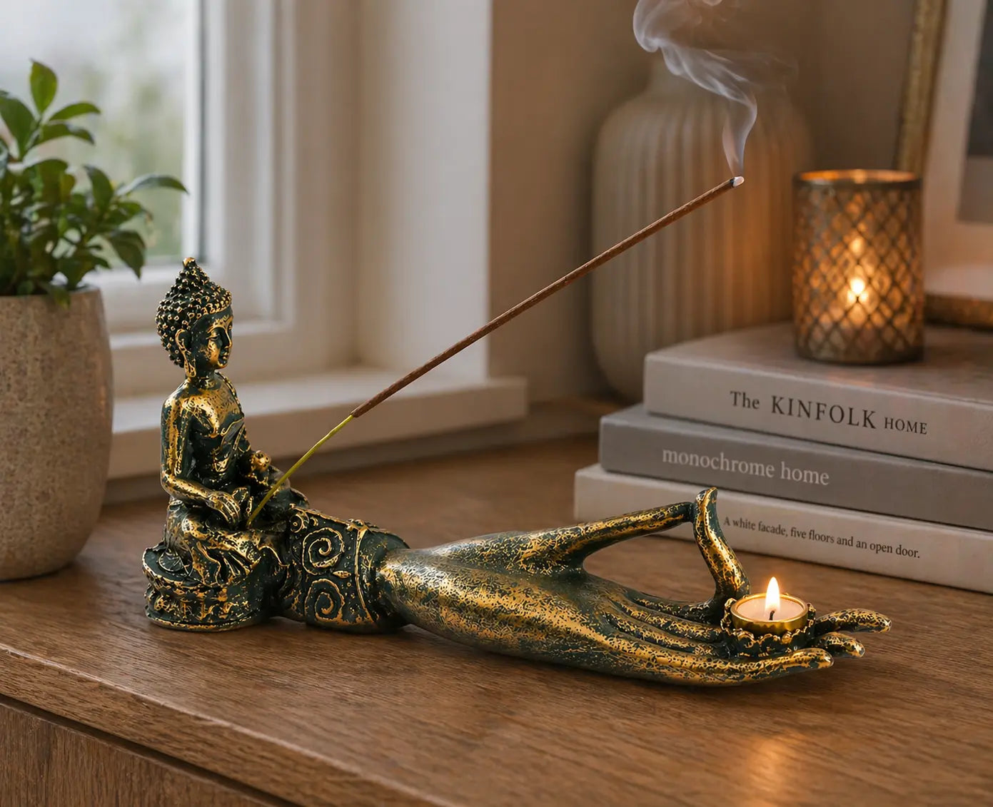 Antique Buddha - Hand Incense Burner displayed on a wooden surface with a gold-toned Buddha figure holding a lit candle, burning incense stick releasing smoke, surrounded by cozy home decor.