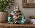Vintage Mint Hand Carved Buddha Statue - 40cm - Happy Buddha with a distressed mint green and brown finish, sitting in a joyful pose on a carved wooden surface next to books and plant decor.
