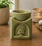 Square Buddha Burner - Light Jade ceramic oil burner with a serene Buddha face carved on the front, displayed on a wooden surface with ambient decorative accents.