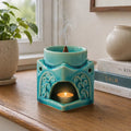 Square Buddha Burner - Soft Turquoise ceramic incense holder with intricate traditional designs, burning incense cone on top and a lit candle inside creating a calming ambiance.