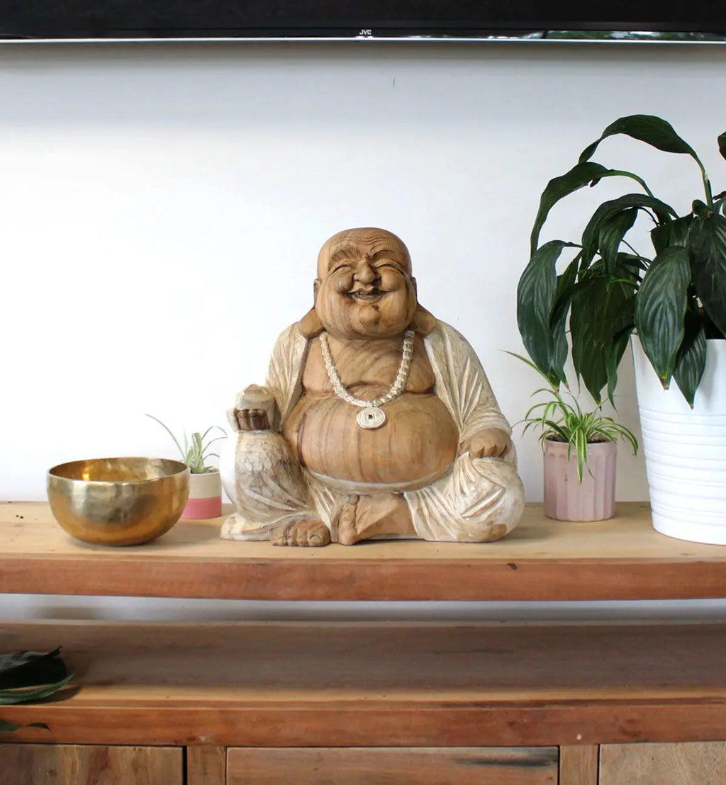 Decorative Happy Buddha - Whitewash 40cm statue seated on a wooden shelf surrounded by green plants and a brass bowl, adding serene Buddha decor to the space.