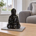 Sitting Buddha Oil Burner - Black on a stone mat in a British sitting room